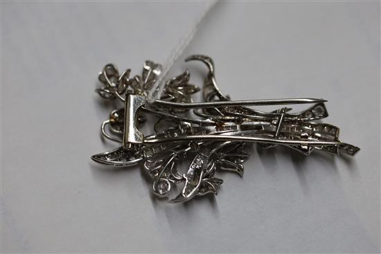 A white metal (tests as 18ct) and graduated baguette and round cut diamond set floral spray clip brooch, 57mm, gross 16.7 grams.